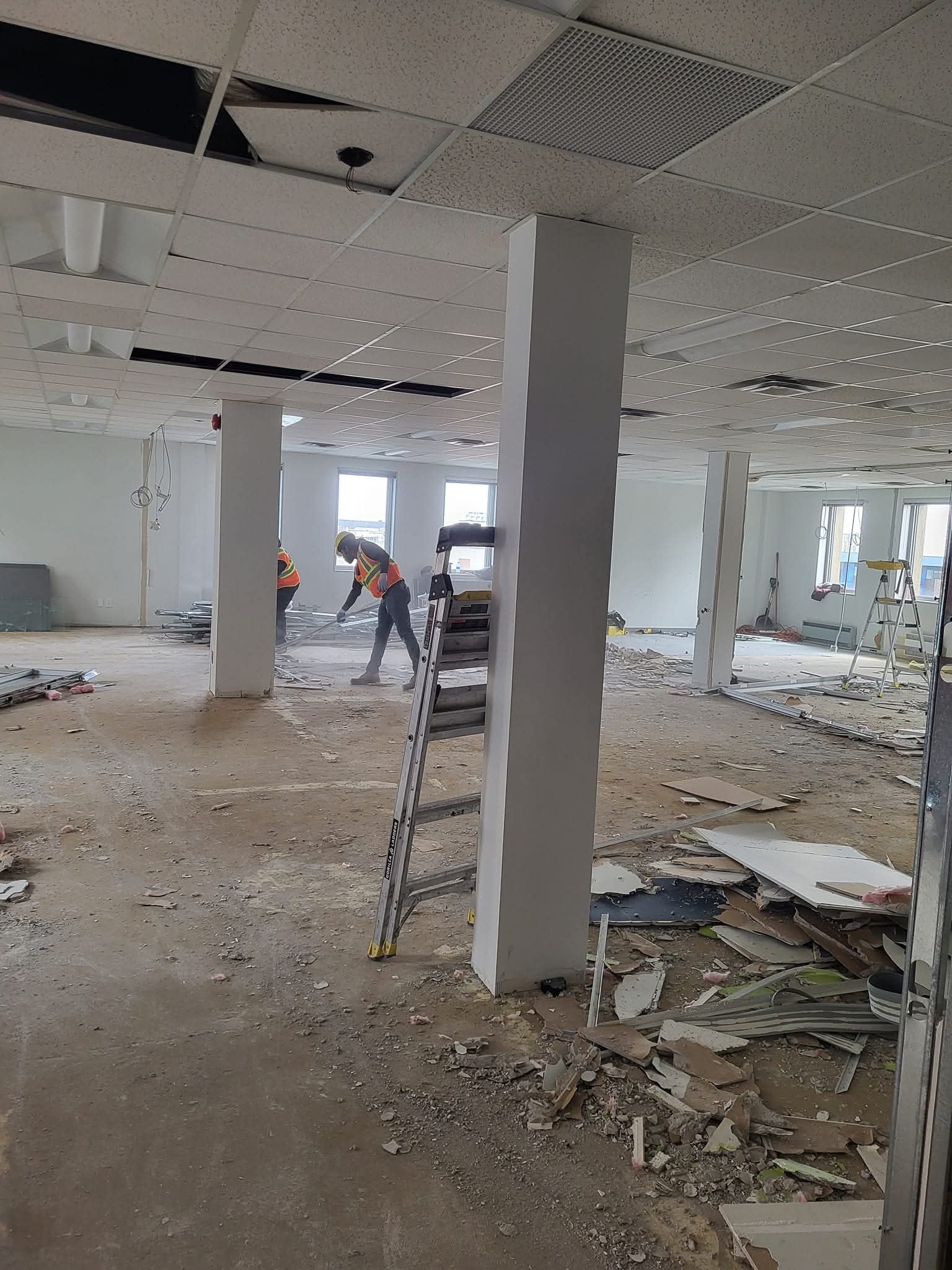 Workers demolishing large empty gym interior
